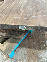 A walnut wood slab with visible grain patterns, marked with measurements on the surface, and a QR label attached.