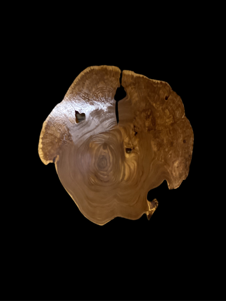 A circular wooden wall hanging art piece with a rustic finish with a black background.