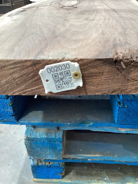 A walnut slab edge with QR code attached.