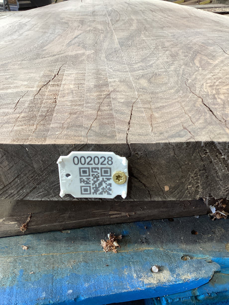 A large walnut wood slab edge with  QR code attached. 