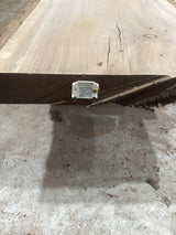 A solid walnut wood slab with visible grain and knots, placed on a concrete surface with a QR code of the sku.