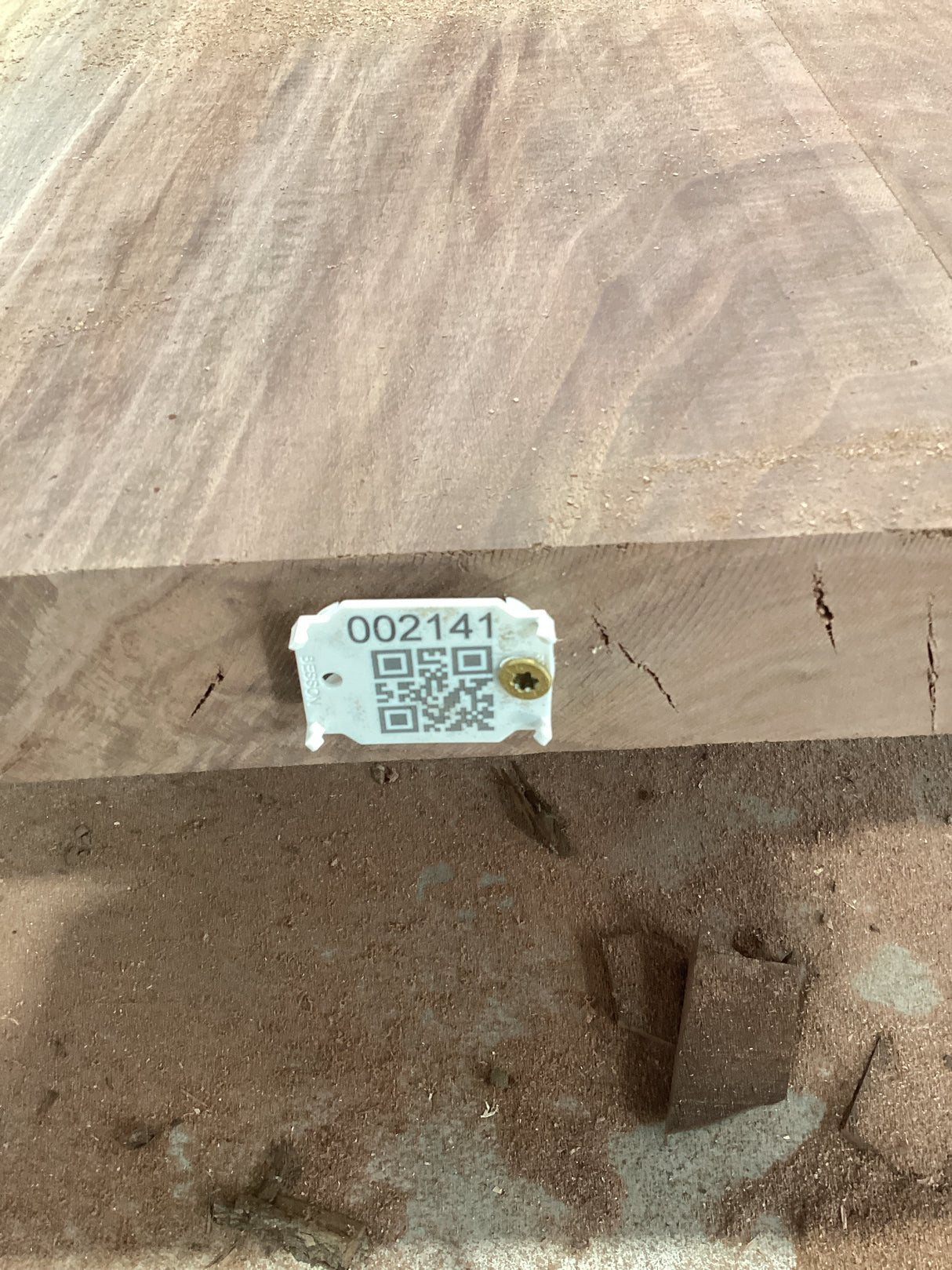A walnut slab with a visible live edge and a tag with a QR code attached to it.