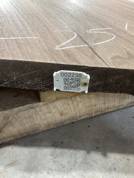 A walnut wood slab with a visible end grain showing the walnut pattern, marked with a white QR label.