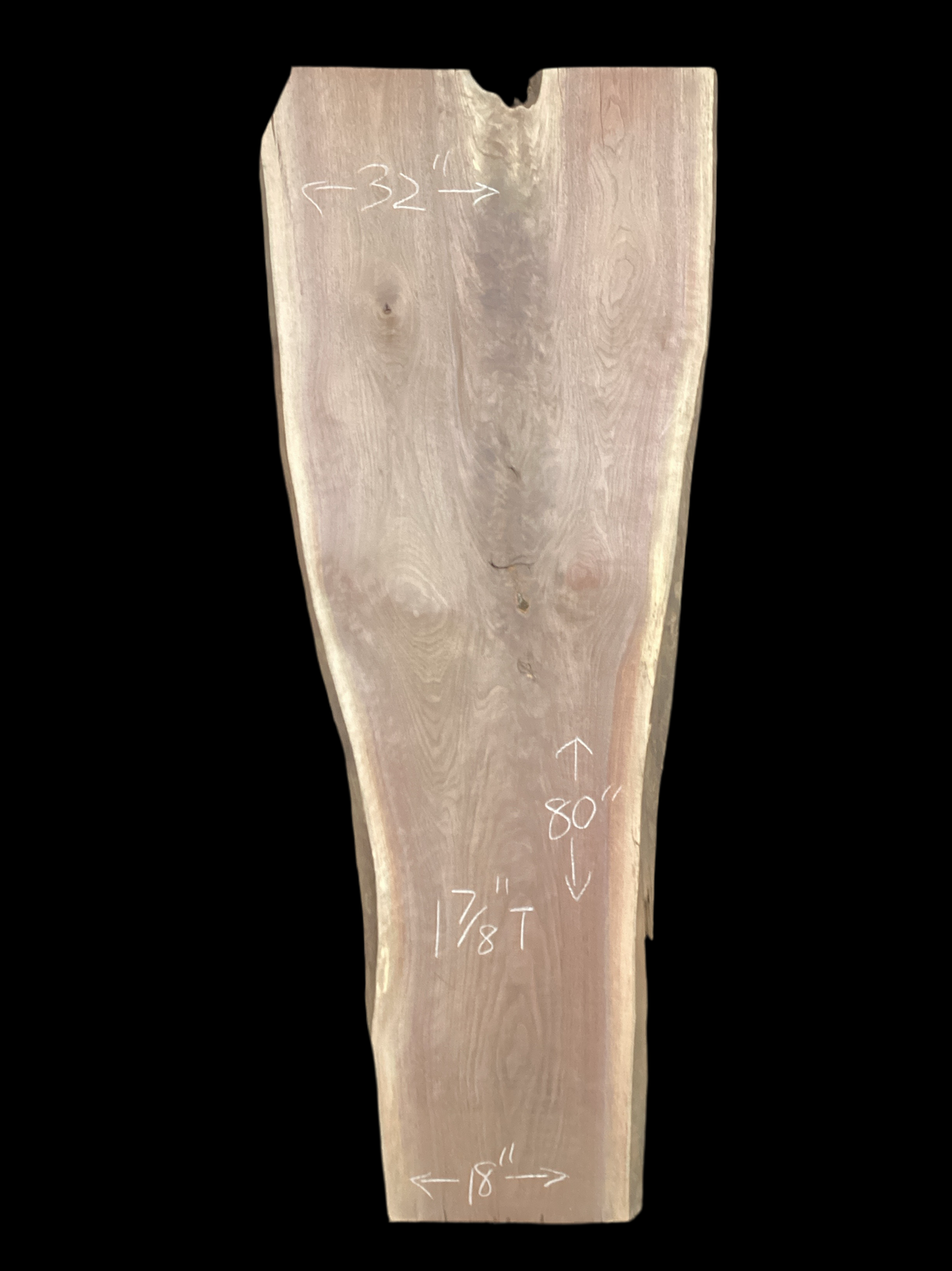 A long walnut slab, wider on one end than the other, and on a black background. 