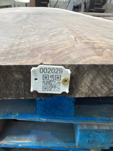 A walnut wood slab edge with QR code attached.