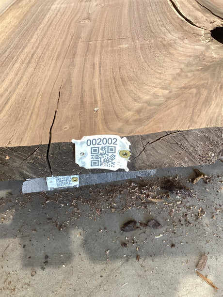 A walnut wood slab edge with QR code attached.