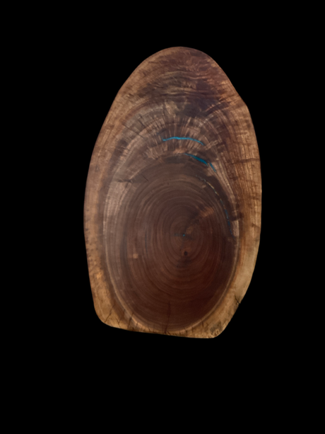 A round black walnut charcuterie board with turquoise and copper epoxy filled cracks on a white background.