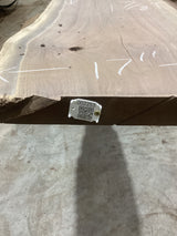 A walnut slab with a QR label indicating its sku, placed on a concrete floor.