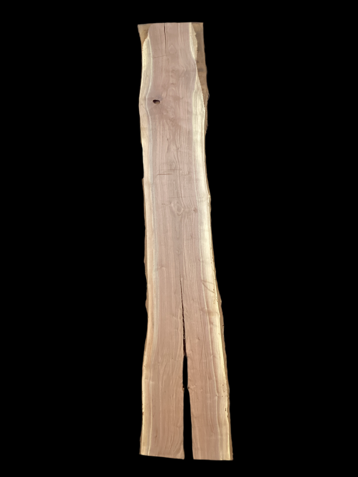 A long walnut wood slab with a split down the middle on a black background.