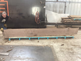 A walnut wood slab propped on pallets and a man standing holding one side up.