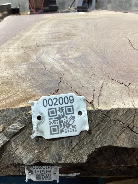 QR label attached to the edge of a walnut wood slab.