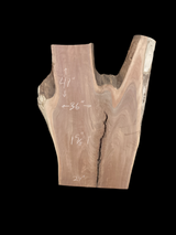 An irregularly shaped walnut slab with a distinctive striped figure pattern on a black background.