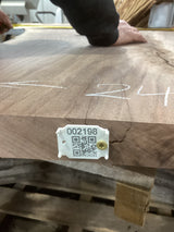 A walnut slab with a unique crotch wood figure, marked with white lines and a tag containing a QR code and number.