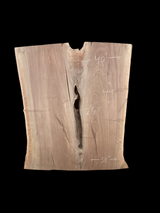 An irregularly shaped walnut slab with a crevasse down the middle on a black background.
