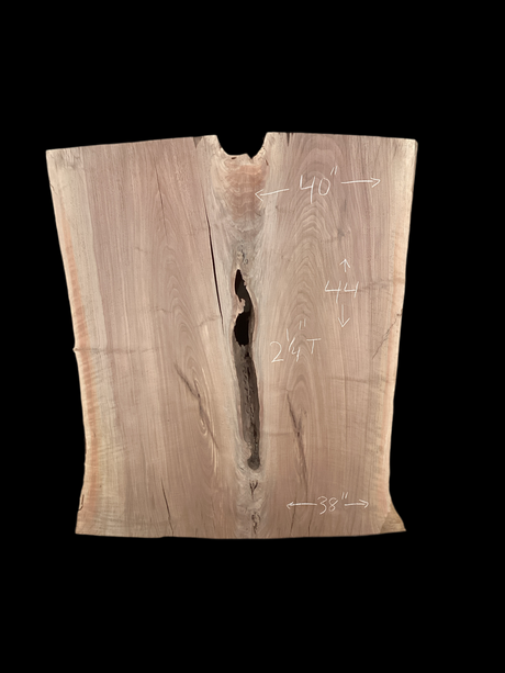 An irregularly shaped walnut slab with a crevasse down the middle on a black background.