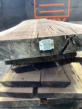 Stacked walnut wood slabs with a visible QR label attached.