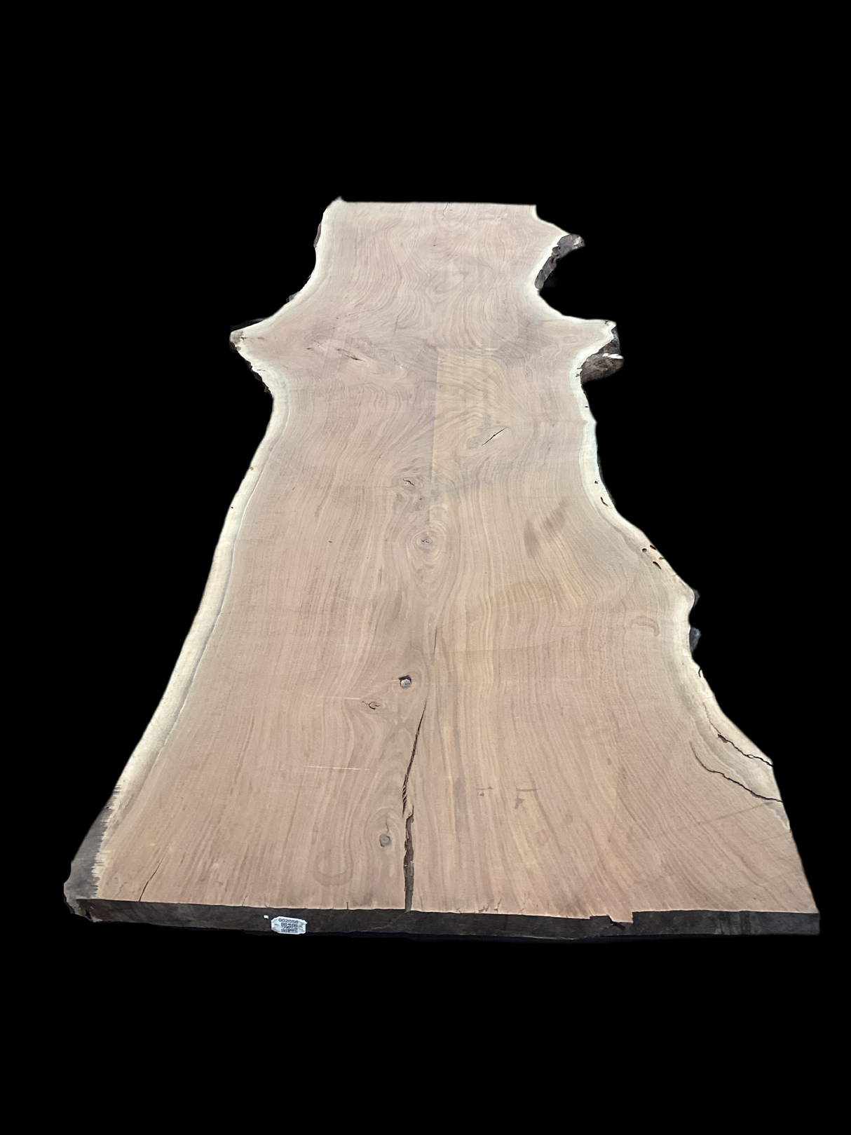 A walnut wood slab with a natural curved edge and a rough, unpolished surface, displayed on a dark background.
