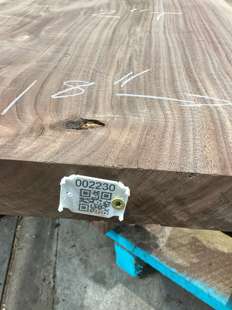 A walnut slab with a visible wood grain pattern and a tag attached to it with a QR code.