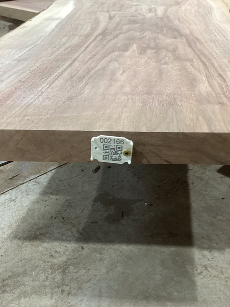 A walnut wood slab with visible natural grain patterns and a QR tag attached to it.