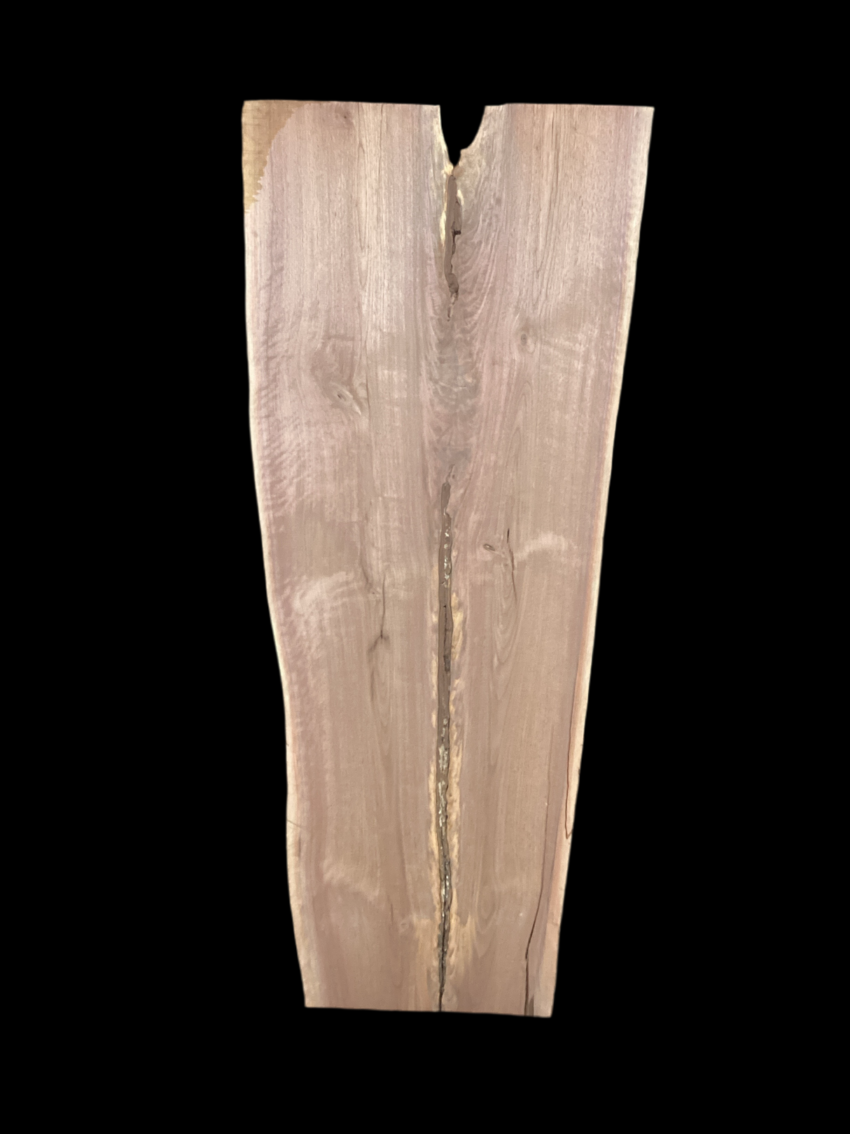 A long walnut slab, wider on one end than the other, and on a black background. 