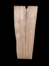 A long walnut slab, wider on one end than the other, and on a black background. 