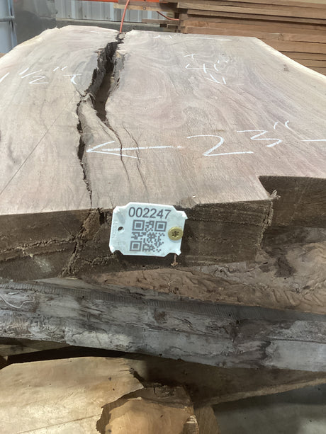 A walnut slab edge with a crevice in the middle and a tag with a QR code attached to it.