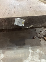 A walnut slab with a visible figure and grain, marked with a tag containing a QR code.