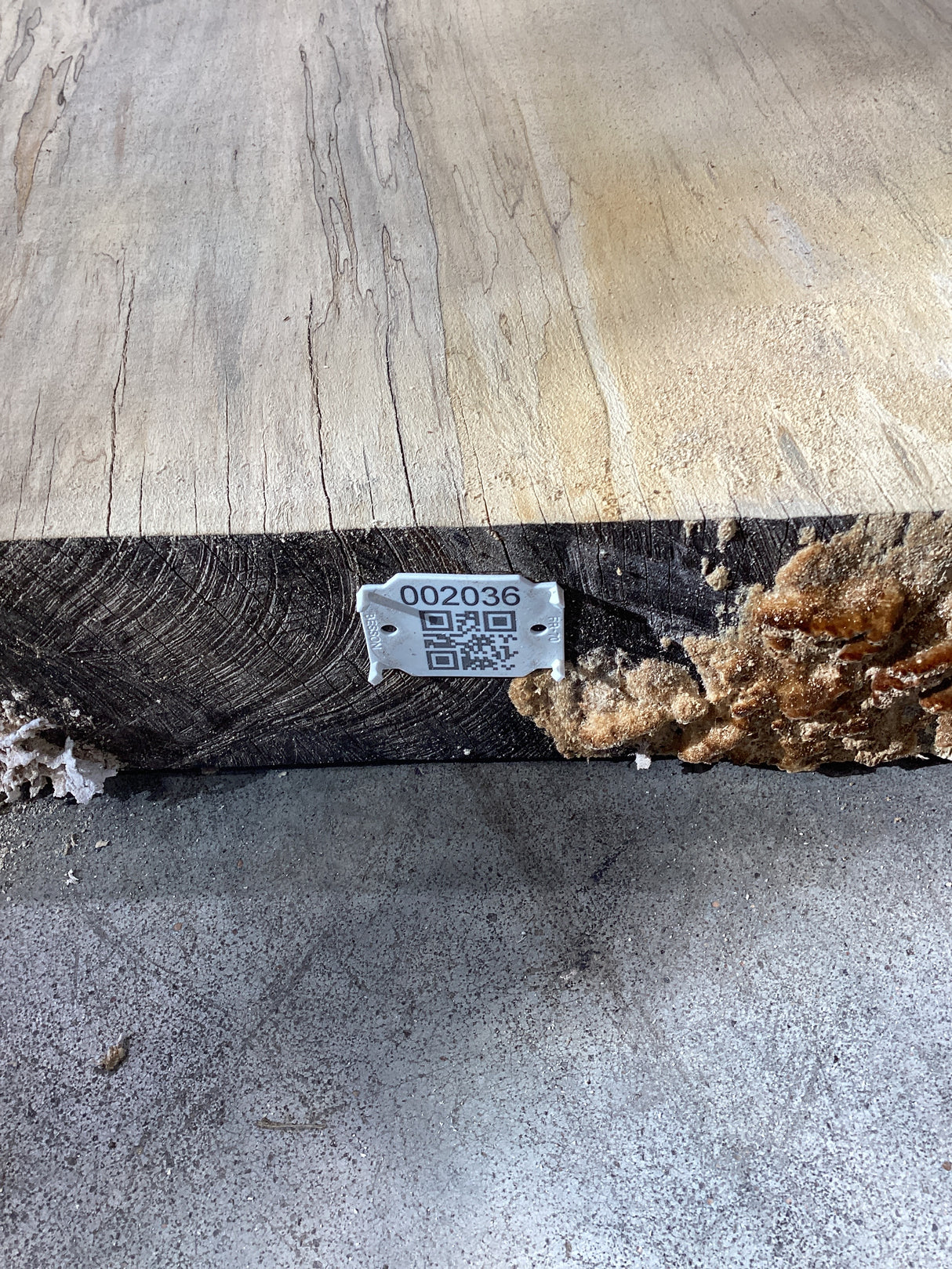 QR label attached to the edge of a wood slab.