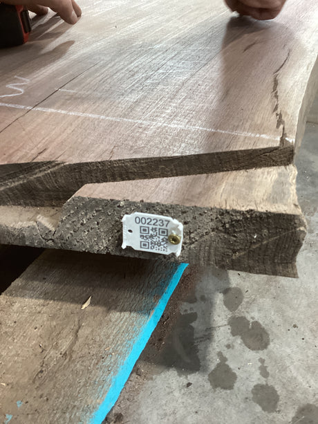 A walnut slab with a visible QR label on it, placed on a wooden surface.