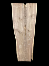 A long walnut slab, wider on one end than the other and on a black background. 