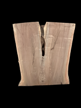 An irregularly shaped walnut slab with a crevasse down the middle on a black background.
