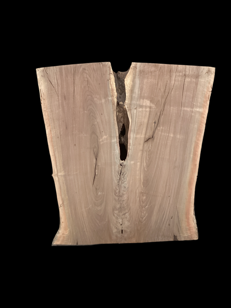 An irregularly shaped walnut slab with a crevasse down the middle on a black background.