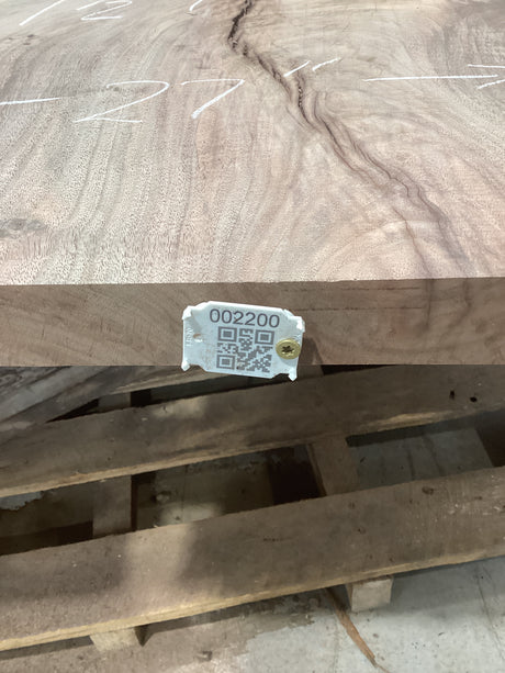 A walnut slab with unique lightning bolt patterns, with an attached tag displaying a QR code and number.