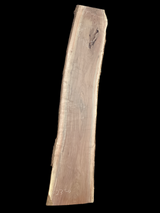 A long walnut wood slab on a black background.