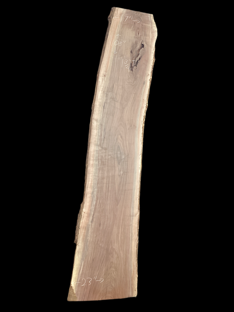 A long walnut wood slab on a black background.