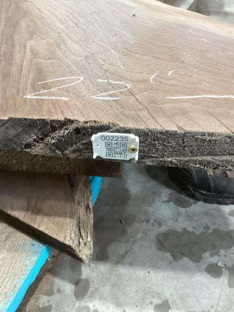 A walnut wood slab with a visible QR label attached to the edge.