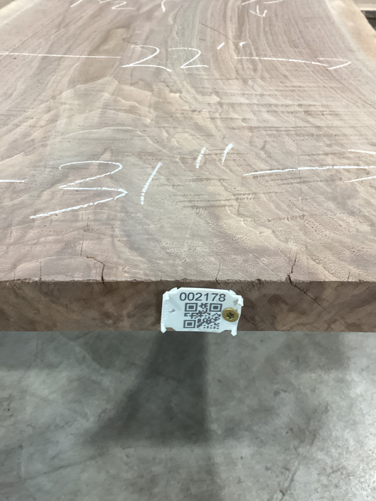 A walnut slab with visible measurements marked on it, indicating it has been cut or processed for furniture making. QR label attached to the edge of the slab.