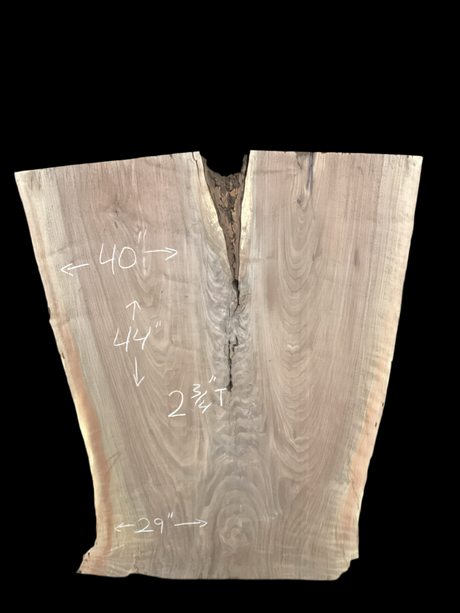 An irregularly shaped walnut slab with a distinctive striped figure pattern on a black background.
