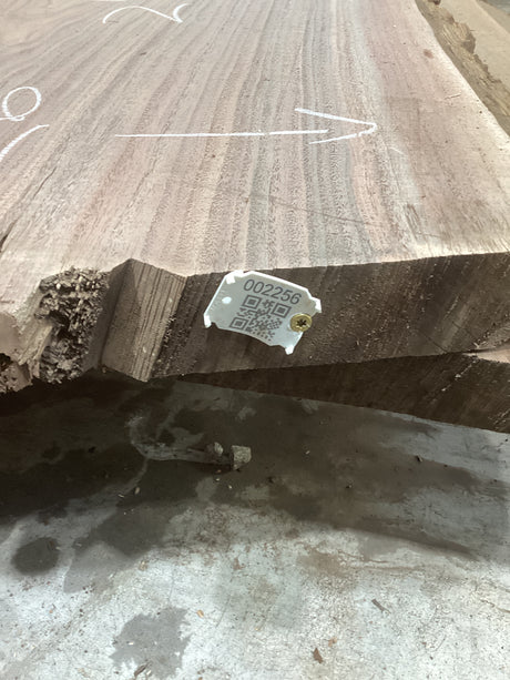 A walnut slab wood material with a visible label in the foreground, indicating the product is a bar top. The wood has a natural grain pattern.