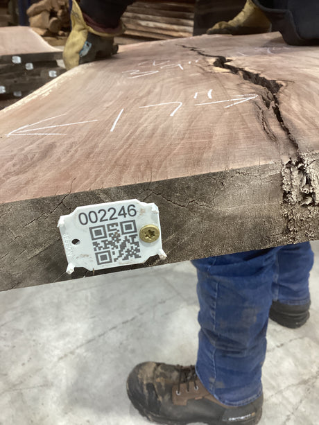 A walnut slab with a tag indicating it is a unique piece with a numerical label and QR code.