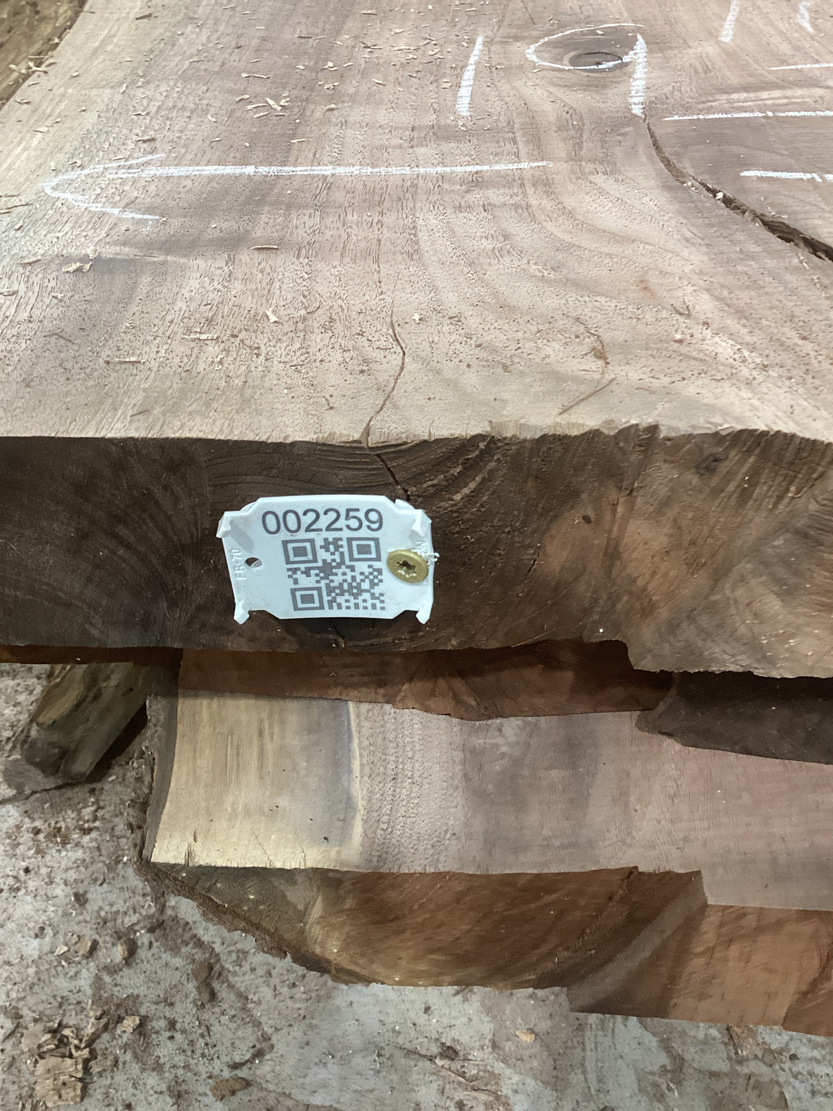 A walnut wood slab with a visible identification tag on the edge, displaying natural grain patterns.