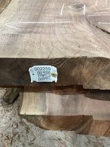 A walnut wood slab with a visible identification tag on the edge, displaying natural grain patterns.