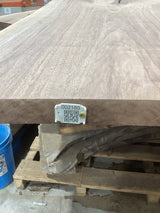 A walnut wood slab with a visible wood grain and a QR label in the foreground.
