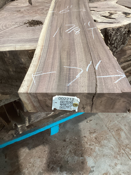 A walnut wood slab with visible grain patterns, marked with white chalk measurements, and a QR tag attached to the front.