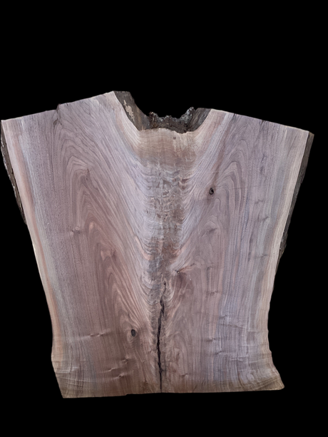 A walnut wood slab with a visible natural edge and a hole at the center, against a black background.