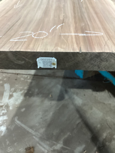 A walnut slab with measurements marked on it, with an attached QR label signifying the sku.