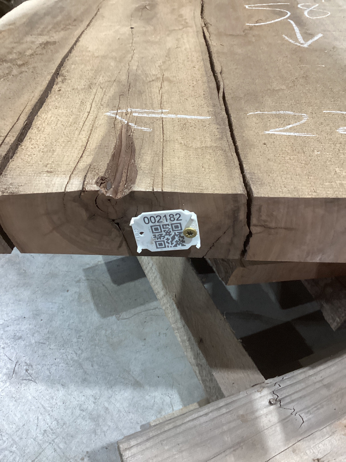 A walnut slab with visible wood grain and cracks, bearing a QR label with a identification number.