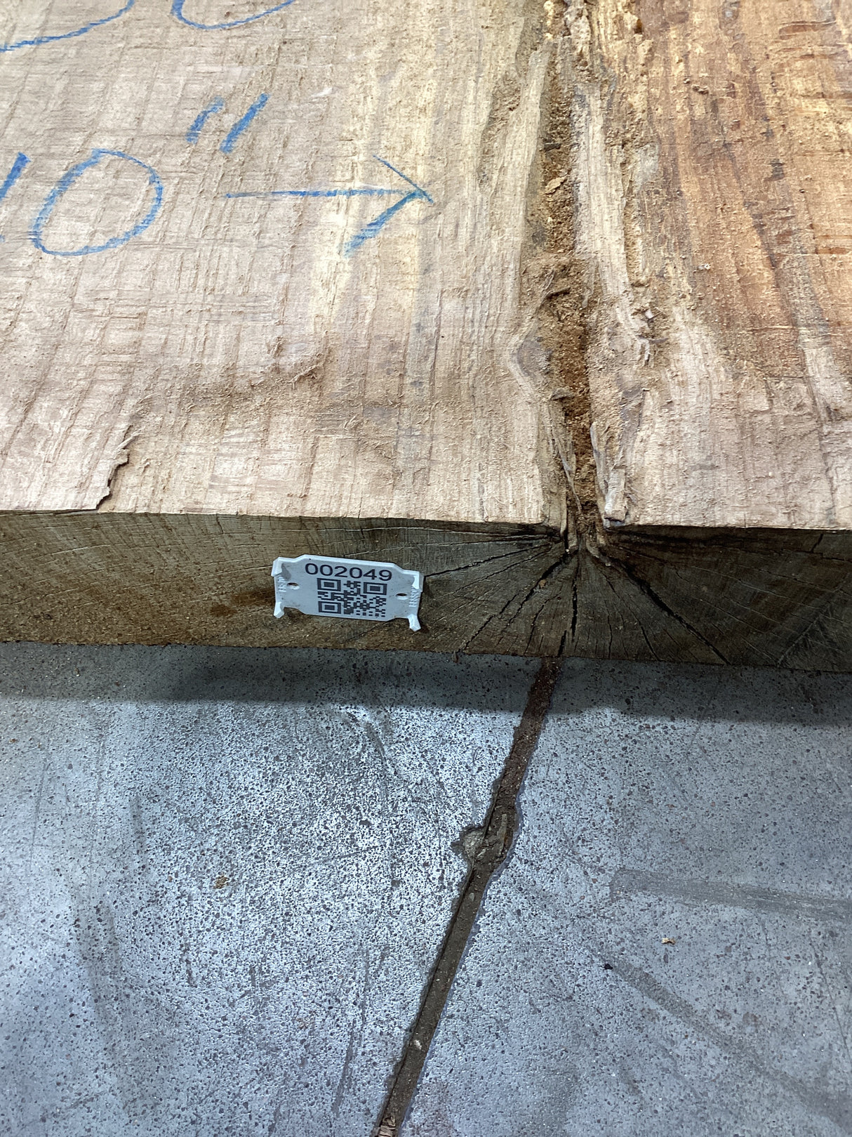 The edge of an unprocessed red oak slab with QR code attached. 