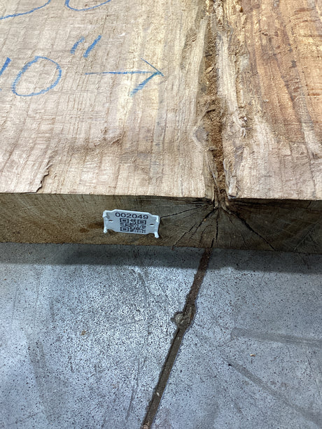 The edge of an unprocessed red oak slab with QR code attached. 