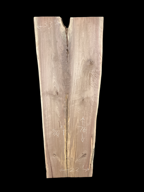 A long walnut slab, wider on one end than the other, and on a black background. 